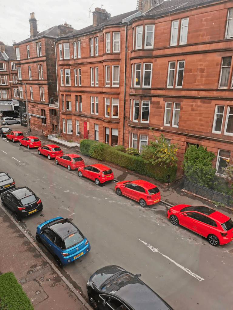 Zdjęcie przedstawiającę siedem takich samych czerwonych samochodów. Jak w Matrixie!